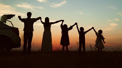 Big family at sunset holding hands, silhouettes. Happy people children parents lined up according to height held hands raised in air with joyful cheerful feeling of freedom anticipation of journey.
