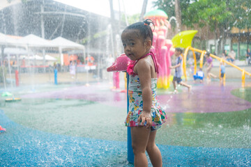 Little preschool asian girl enjoying play in outdoor water park playground