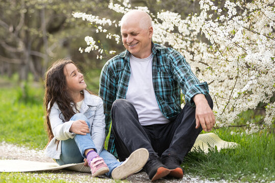 Smiling child hugging her happy grandfather - outdoor in nature.