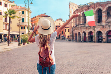 Rear view of woman holding Italian flag in Verna city- Travel destination, tour tourism in Italy,...