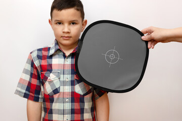 In the photo studio, a gray card is placed next to the boy to register the correct camera colors....