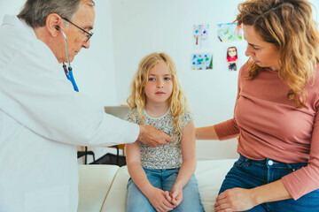 Professional doctor checking child during medical checkup in clinic office - Pediatrician using...