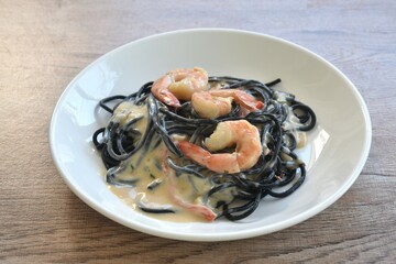 black squid ink spaghetti with shrimp dressing white carbonara cream sauce on plate 