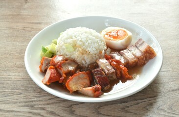 roasted barbecue and crispy pork slice topping plain rice with boiled egg dressing sweet red gravy sauce on plate 