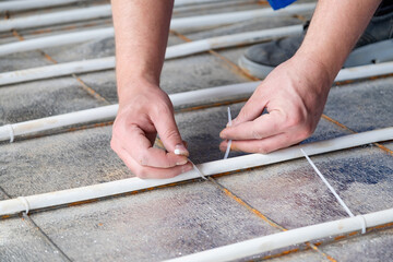 man worker takes measurements during the installation of a warm floor