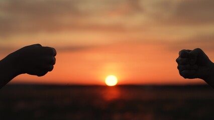 Hands clashing fists brofist at sunset in field. Farmers workers colleagues employees partners...