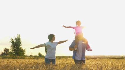 Happy family running flying at sunset dry wheat field together slow motion. Overjoyed father mother and daughter having fun flight plane fantasy imagination enjoy freedom outdoor leisure activity