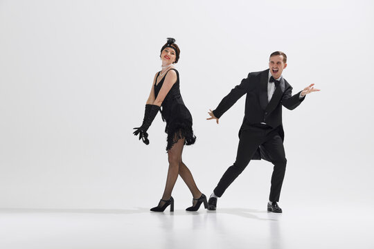 Joyful depiction of 1920s dance culture, young couple dressed in period costumes performing with enthusiasm isolated over white studio background. Concept of art, retro and vintage, entertainment, 20s