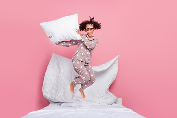 Photo of funky excited lady wear pajama rising pillow jumping high isolated pink color background