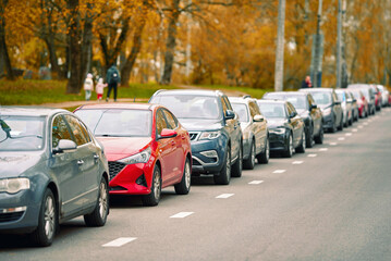 Crowded parking lot with cars parked tightly along the roadside. Cars in rows along the roadside,...