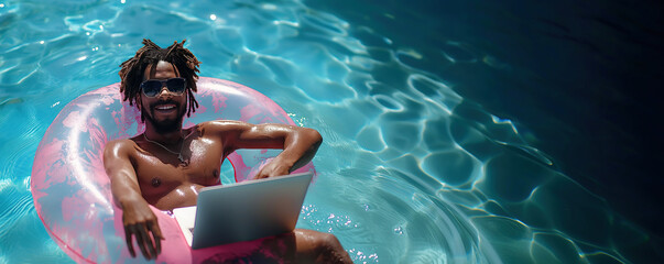 happy black male freelancer in sunglasses is working on laptop swimming in pool on pink swimming circle