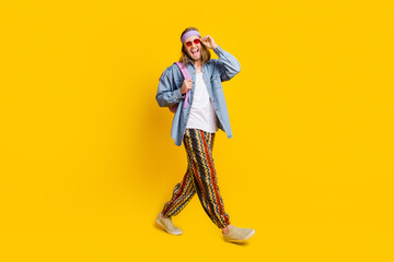 Full size photo of cool young man walk empty space wear denim shirt isolated on yellow color background