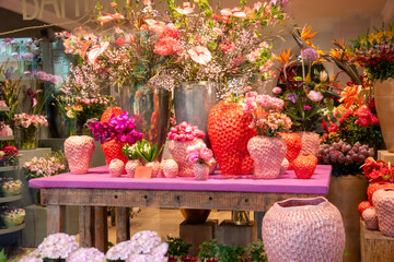 Strawberry season. View into the window of a flower shop. Vases in the shape of strawberries