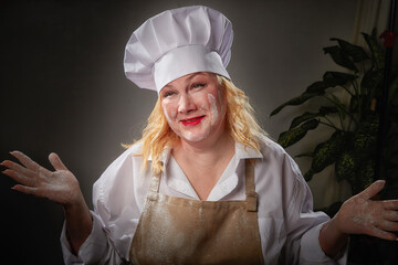 A fat funny female cook in a hat and apron poses in the kitchen and takes a selfie. Good cooking...