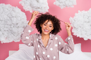 Photo of funky carefree lady wear pajama holding hair curls smiling isolated pink color background