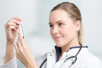 young female doctor is checking a blood probe in her hand