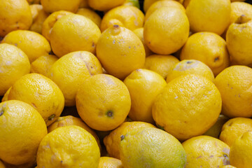 Lemons on the market. Juicy lemons background. Yellow fruits. Heap of ripe lemons. Yellow color background. Citrus harvest. Healthy eating. Vitamins and antioxidant.