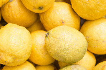 Lemons on the market. Juicy lemons background. Yellow fruits. Heap of ripe lemons. Yellow color background. Citrus harvest. Healthy eating. Vitamins and antioxidant. 