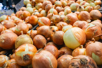 Yellow onions on market stall. Unpeeled onions in box. Onion bulbs background. Heap of organic vegetables. White onion harvest. 