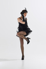 Elegant young woman, dancer styled in Roaring Twenties attire, performing solo Charleston dance...