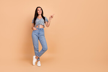 Photo of cute lovely cheerful woman wear blue trendy clothes demonstrate empty space isolated on beige color background