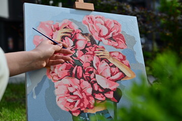  A female artist sits by her easel, painting a picture.


