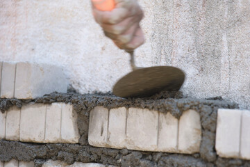 Worker using trowel to put cement mortar on wall