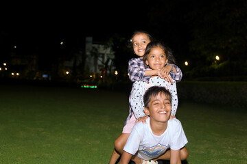 Happy three kids family playing together in the park at night time Lifestyle concept