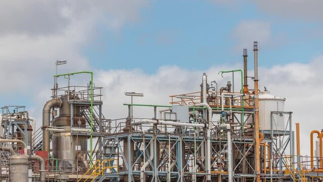 Distillation Columns and their process equipment of hydrogen plant timelapse with clouds on a background. Many pipes and tanks of industrial factory against a sky