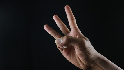 Male hand gesture number three closeup isolated on a black background