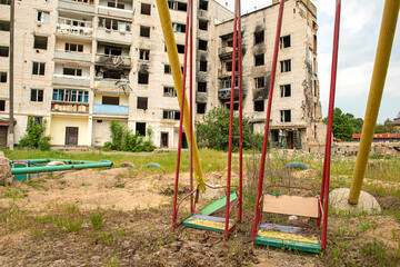 Destroyed burnt buildings after a fire and a rocket hit and a children's swing in the yard....