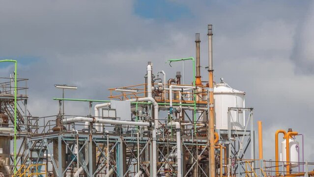 Distillation Columns and their process equipment of hydrogen plant timelapse panorama with clouds on a background. Many pipes and tanks of industrial factory against a sky