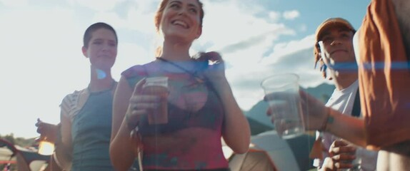 Diverse group of friends enjoying drinks and laughter at an outdoor music festival