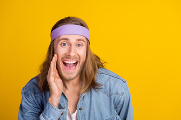 Photo portrait of attractive young hippie man share secret cover mouth wear trendy denim outfit isolated on yellow color background