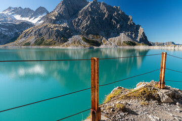 view at a barrier lake in the mountains with a rusty fence in front