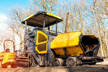 Yellow asphalt paver filled tarmac laying new road building site