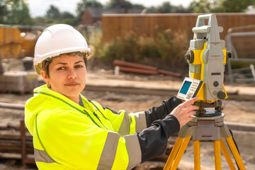 concentrate mature woman site engineer surveyor working with theodolite equipment on building site