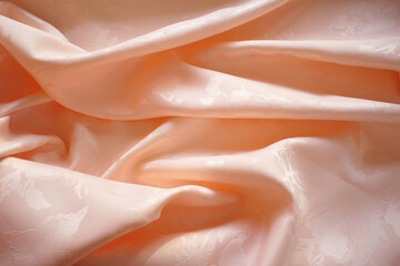 Peach silk or satin crumpled fabric background. Beautiful, elegant and delicate texture. 