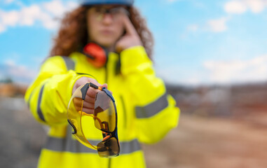 Female safety manager gives protective glasses mandatory to wear in building construction