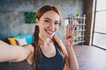 Photo of young pretty fitness girl make selfie show v-sign sportswear training apartment indoors