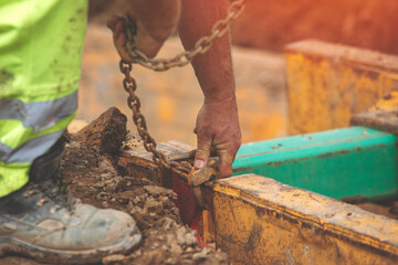 close-up of hands of builder attaching fixing lifting gear hook and chain to safety shore system...