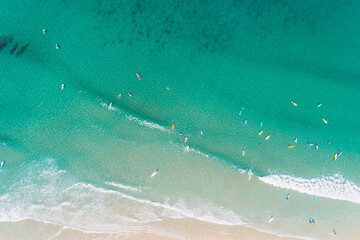 aerial shot, overhead view with drone of a beach shore with people learning to surf, school of surf...