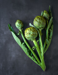 Overhead view of fresh artichokes on a gray surface; copy space