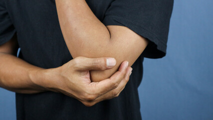 Elbow pain concept : Close up man holding on elbow and feeling a pain.