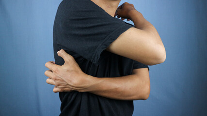 Asian young man scratching his back isolated blue background
