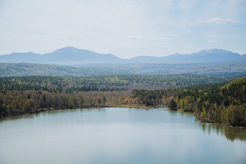 Obraz premium A lake lies in a forest with mountains framing the skyline
