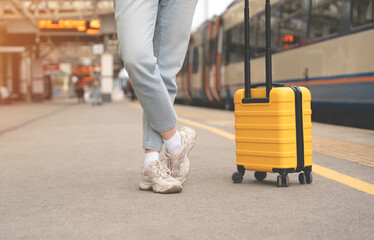 leg of woman with suitcase at railway station train is arriving 
