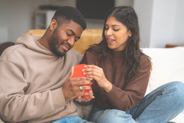 man giving gift woman sitting on sofa at home Real people lifestyle