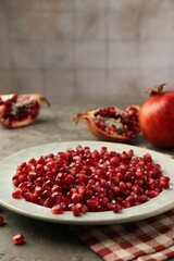 Tasty ripe pomegranate grains on grey table