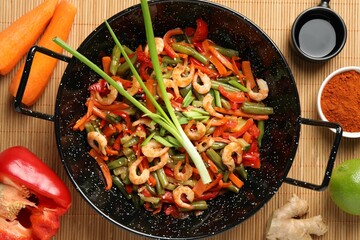 Shrimp stir fry with vegetables in wok and ingredients on table, flat lay